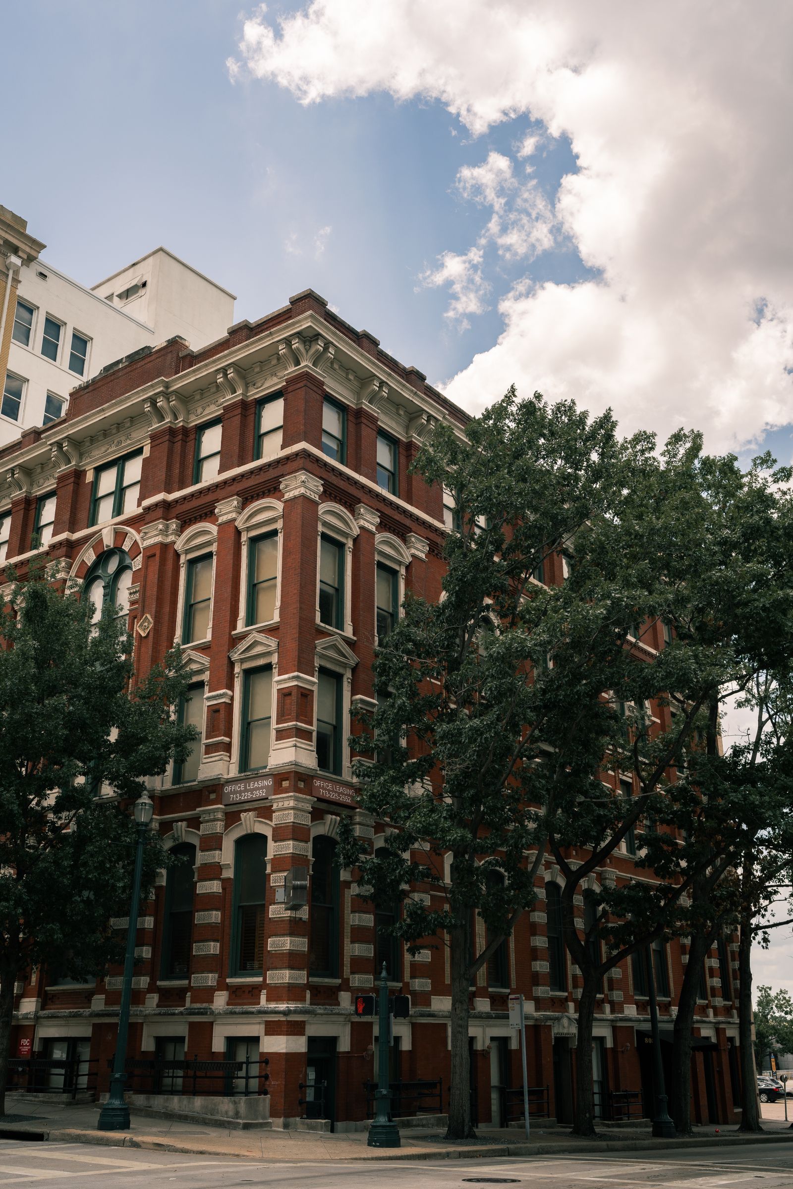 Historic red-brick downtown building framed by mature trees